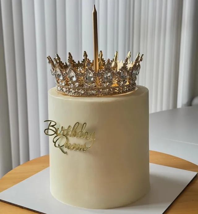 עוגה לבנה גבוהה עם כתר זהב וכיתוב Birthday Queen
